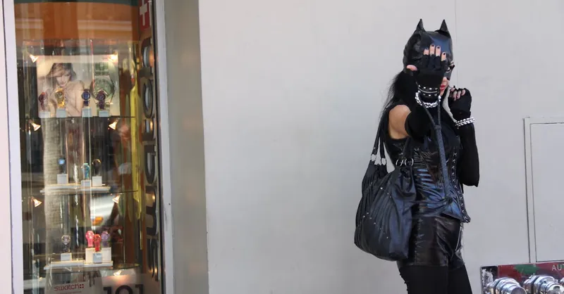Street-style photo of a woman in Catwoman costume posing outside a fashion store.