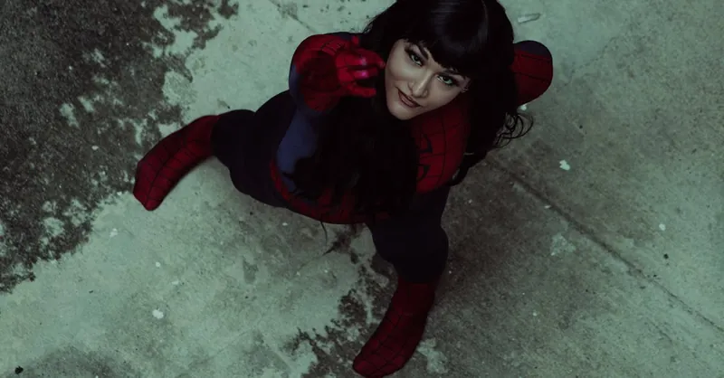 Woman in Spider-Man costume striking a dynamic pose from an overhead view on worn pavement.