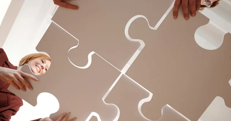 Low angle view of diverse team assembling large puzzle pieces, symbolizing unity and cooperation.