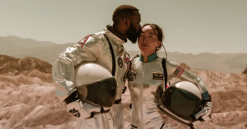 Interracial couple in space suits embracing in a desert landscape, symbolizing exploration and love.