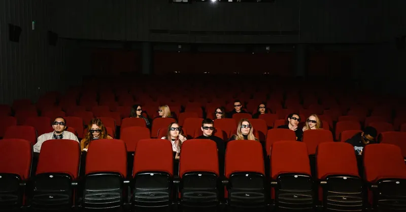 People watching a movie wearing 3D glasses in a near-empty cinema hall.
