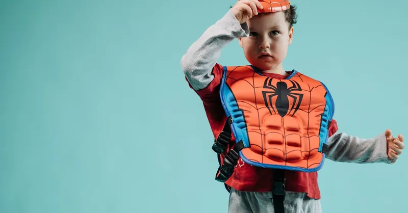Young child wearing a Spiderman costume with a turquoise backdrop, ideal for superhero and child-themed photography.