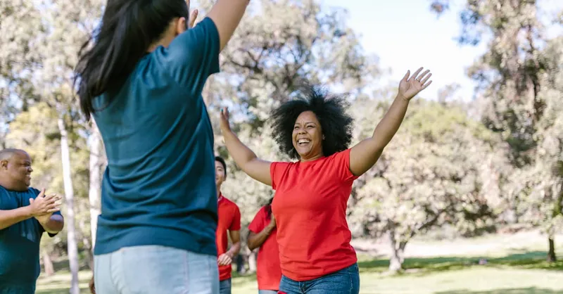 Diverse group of adults engaged in a lively outdoor team-building activity, fostering unity and enjoyment.