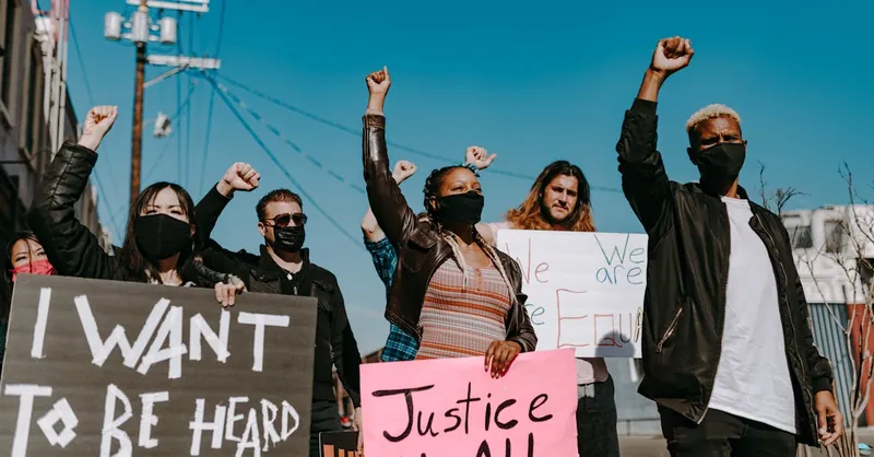 A diverse group of people protesting for justice and equality with banners.