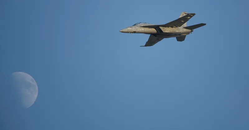 A military jet soaring through the sky with the moon in the background, symbolizing speed and power.