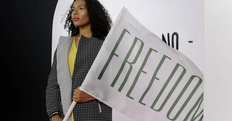 A woman with curly hair holding a Freedom flag indoors. Modern and powerful imagery.
