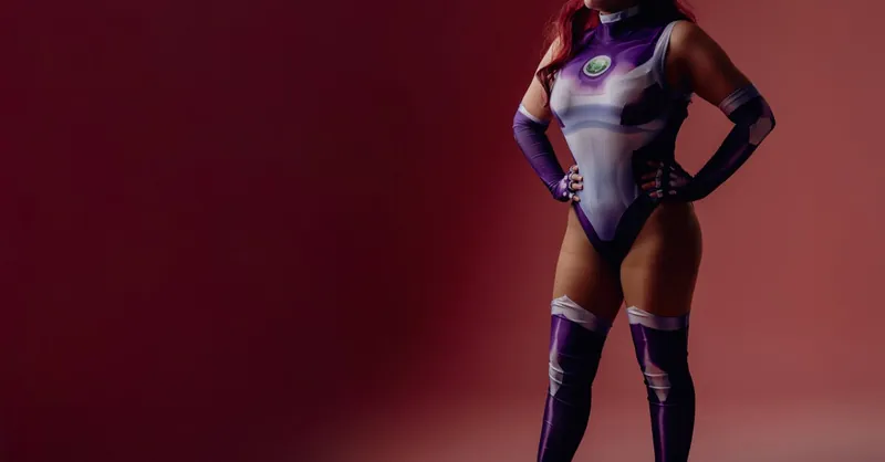 Colorful cosplay of a woman in superhero attire against a pink backdrop.
