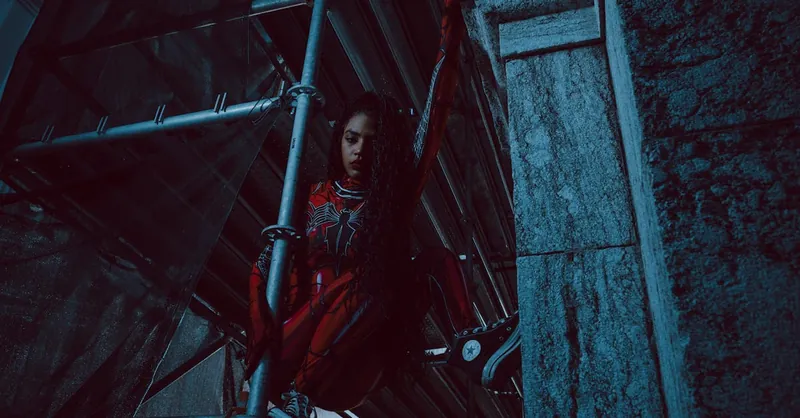 A woman in a Spider-inspired costume clings to scaffolding, showcasing strength and agility.