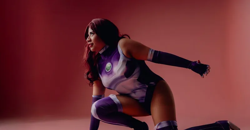 Vibrant cosplay of female superhero in purple costume on pink backdrop.