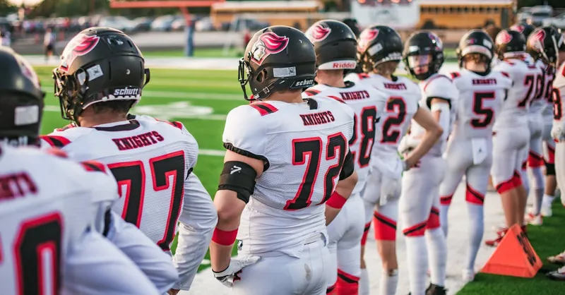 High school football players in white uniforms preparing for a game in Idaho Falls.