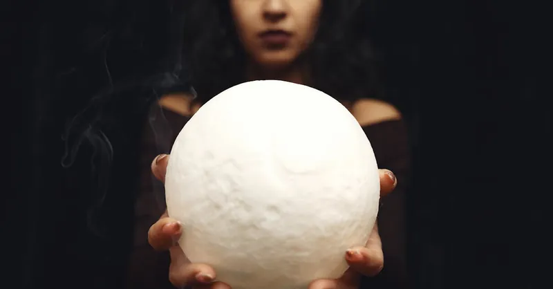 A woman holds a glowing orb with smoke in a mystical atmosphere.