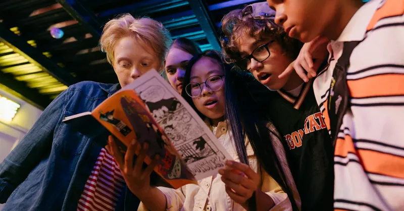 Group of diverse teenagers reading a comic book indoors, showcasing friendship and excitement.