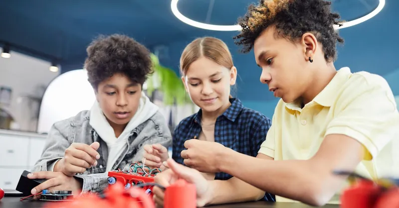 Diverse teenagers collaboratively working on a robotics project in a workshop.